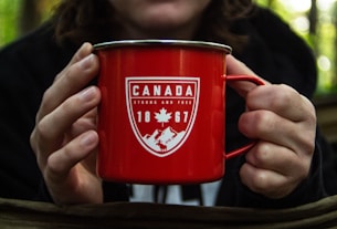 person holding red metal mug