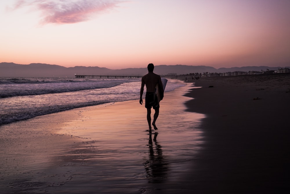 silhouette dell'uomo che cammina lungo la riva del mare