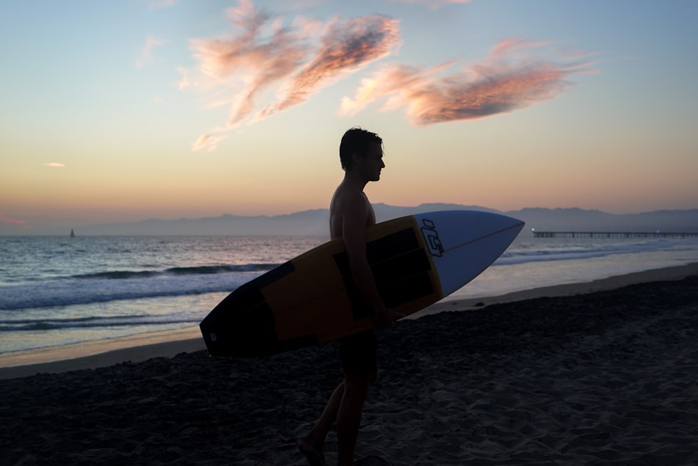 Homem segurando prancha de surf na costa