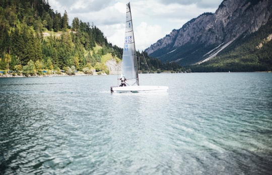 white sailboat on body of water in Plansee Austria