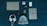 On a dark teal surface, a variety of items are neatly arranged. The items include a Dell laptop, a silver iPad, a white beanie hat, white headphones, a smartphone with a dark case, a black fitness tracker, a white cylindrical speaker, a white external hard drive, and a small USB drive.