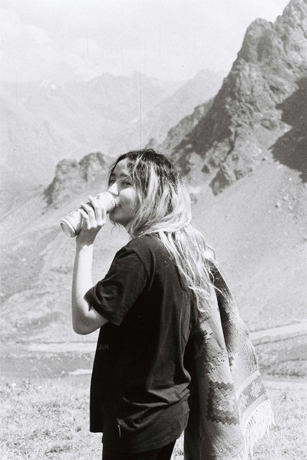 grayscale photography of woman drinking near mountain
