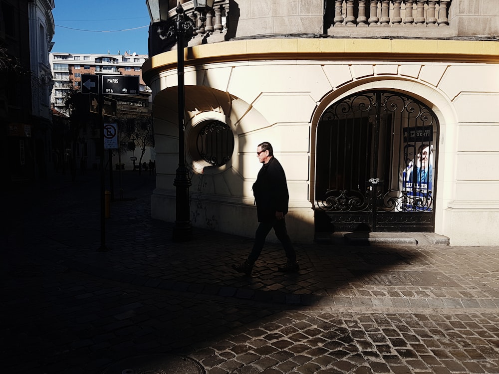 man walking near white concrete wall