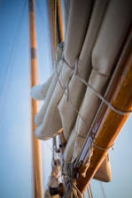 Close-up of classic wooden sailboat rigging with Venetian lagoon in the background.