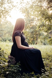 woman sitting on tree stump surrounded by plants