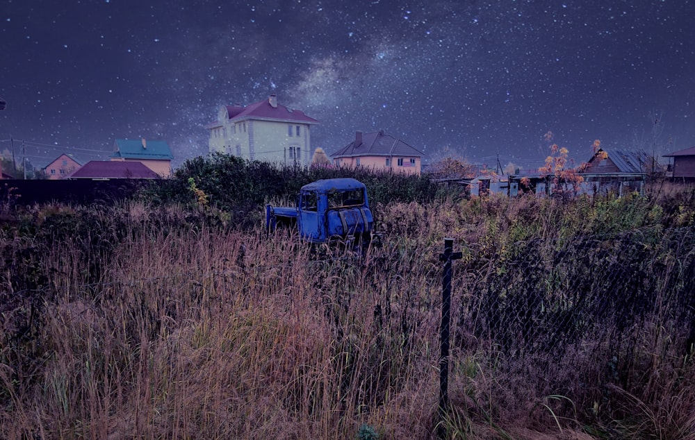 vehículo azul en campo de hierba con casas a distancia