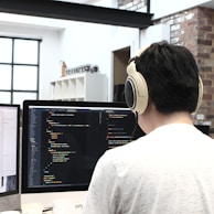 man wearing headphones while using computer