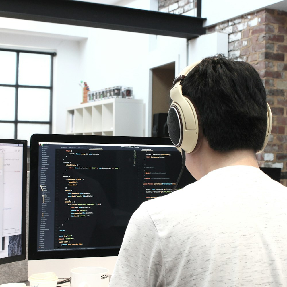 man wearing headphones while using computer