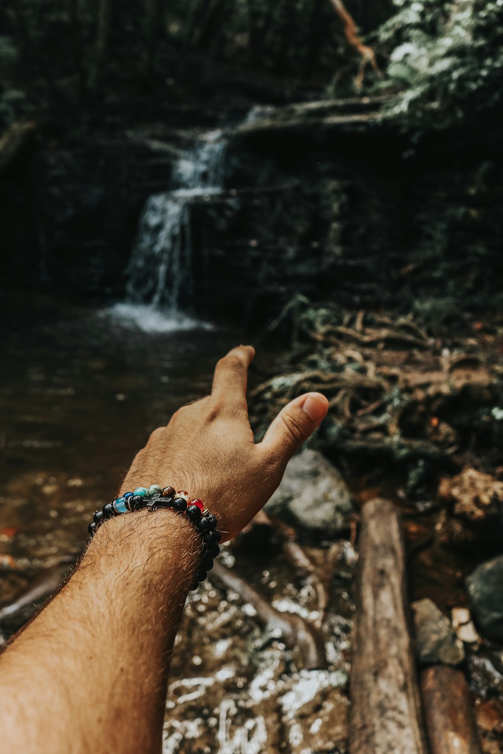 a hand reaching for a waterfall in the woods