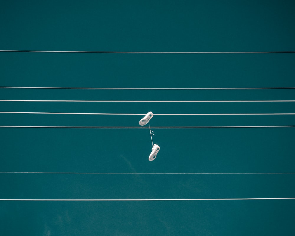 Paar weiße Schuhe, die an einem Kabel hängen