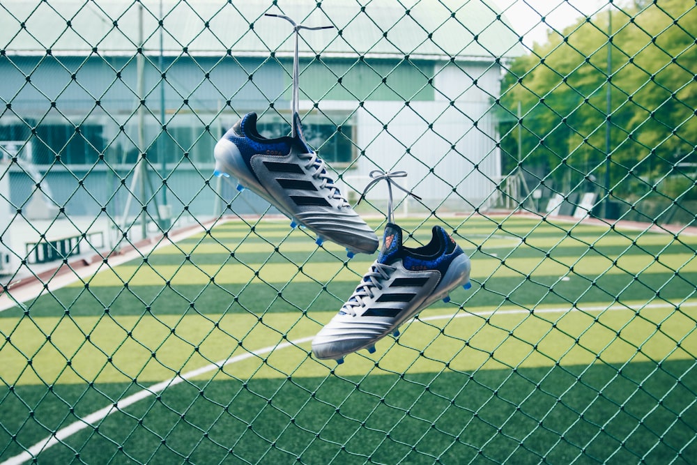 pair of soccer cleats on cyclone fence