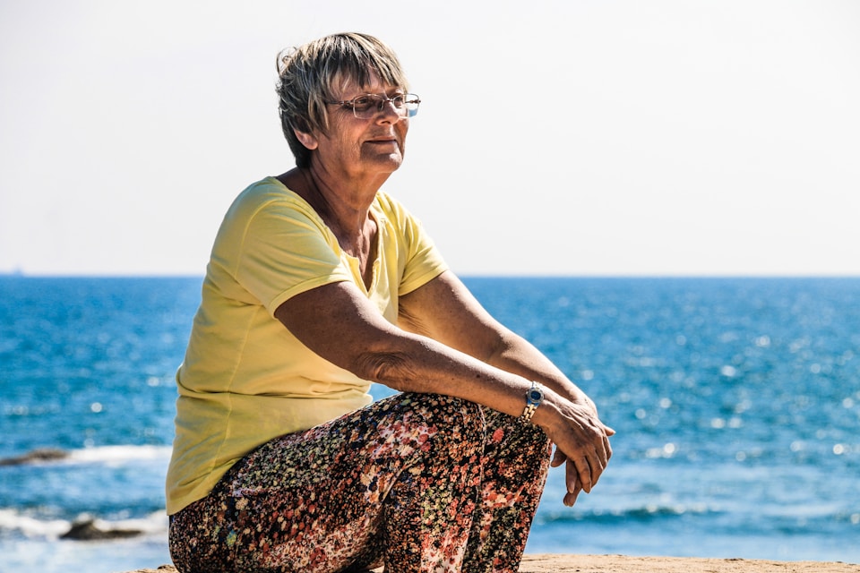 A happy senior woman enjoying the beach, representing an active and healthy quality of life.
