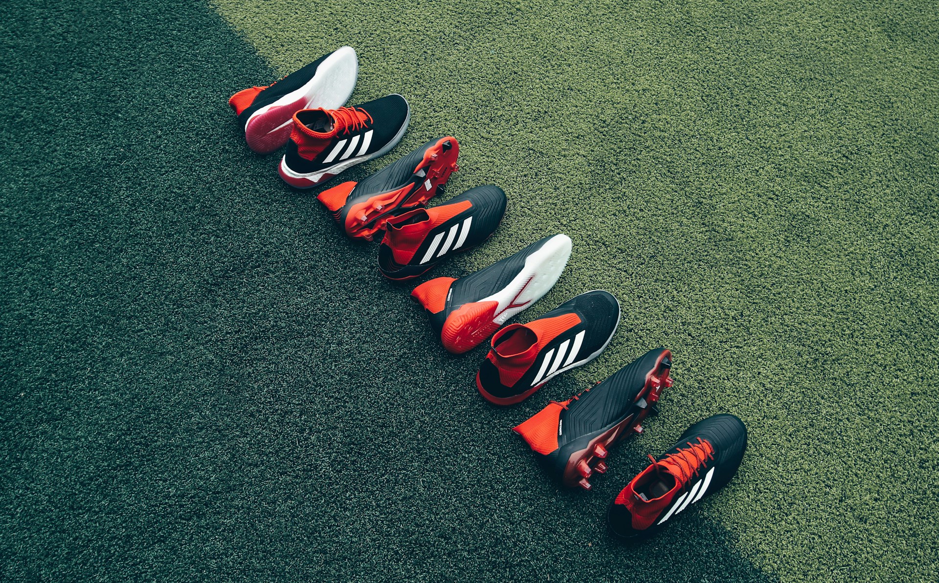 four pairs of black-and-orange shoes laid on green grass