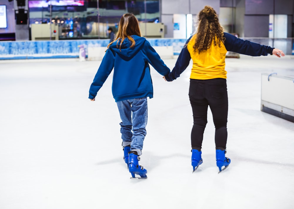 two women holding each other while doing ice skating