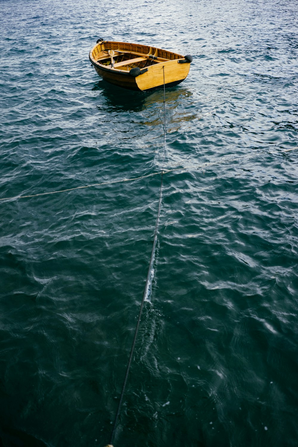 Bote marrón en el cuerpo de agua con cuerda negra durante el día