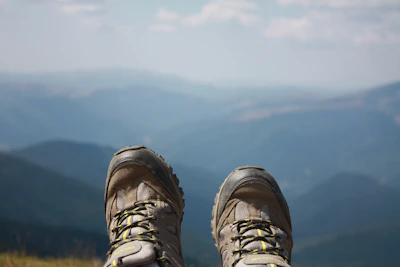 Sturdy trekking boots on a dirt trail with panoramic mountain views in the background