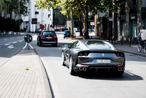 A shiny red Ferrari cruising through an elegant city street under golden evening light.