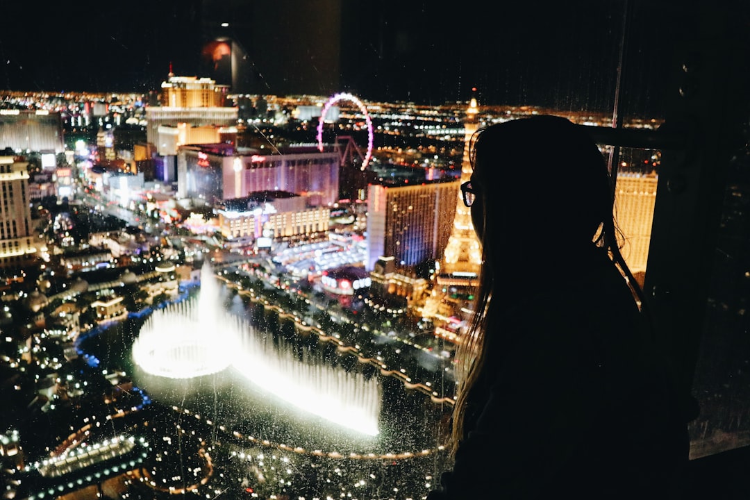 woman standing near edge of building watching at fountain in front of Las Vegas Paris building, Las Vegas view from Cosm