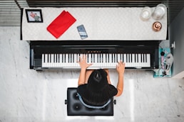 woman playing piano near white wall inside room