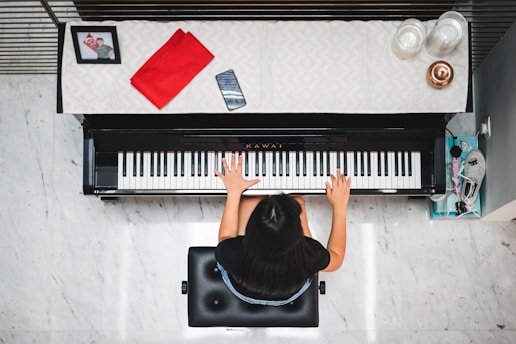 woman playing piano near white wall inside room