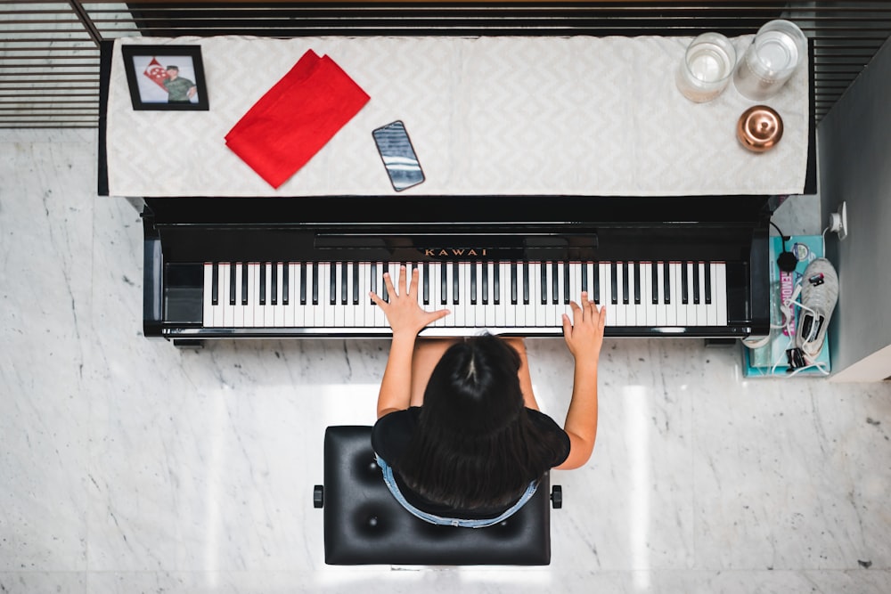 Donna che suona il pianoforte vicino al muro bianco all'interno della stanza