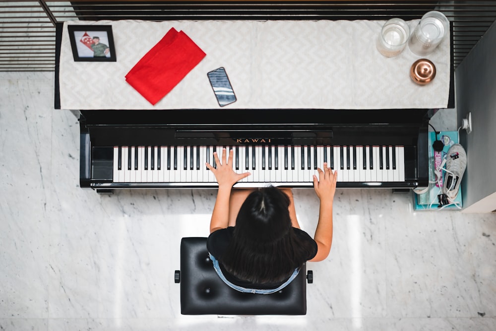 woman playing piano near white wall inside room