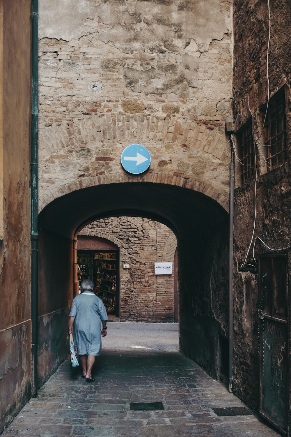 woman walking in gray and brown alley during daytime