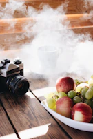 Close-up of a rustic wooden table topped with fresh farm produce and a vintage camera capturing the scene.
