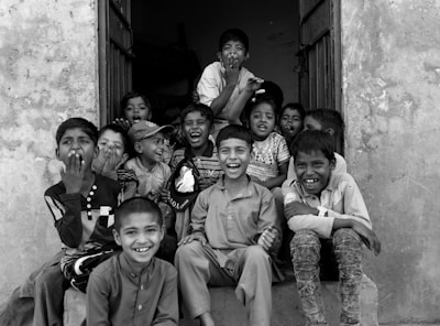 A cheerful group of children wearing various bright outfits from Pirulitoepipa, sitting together and laughing.