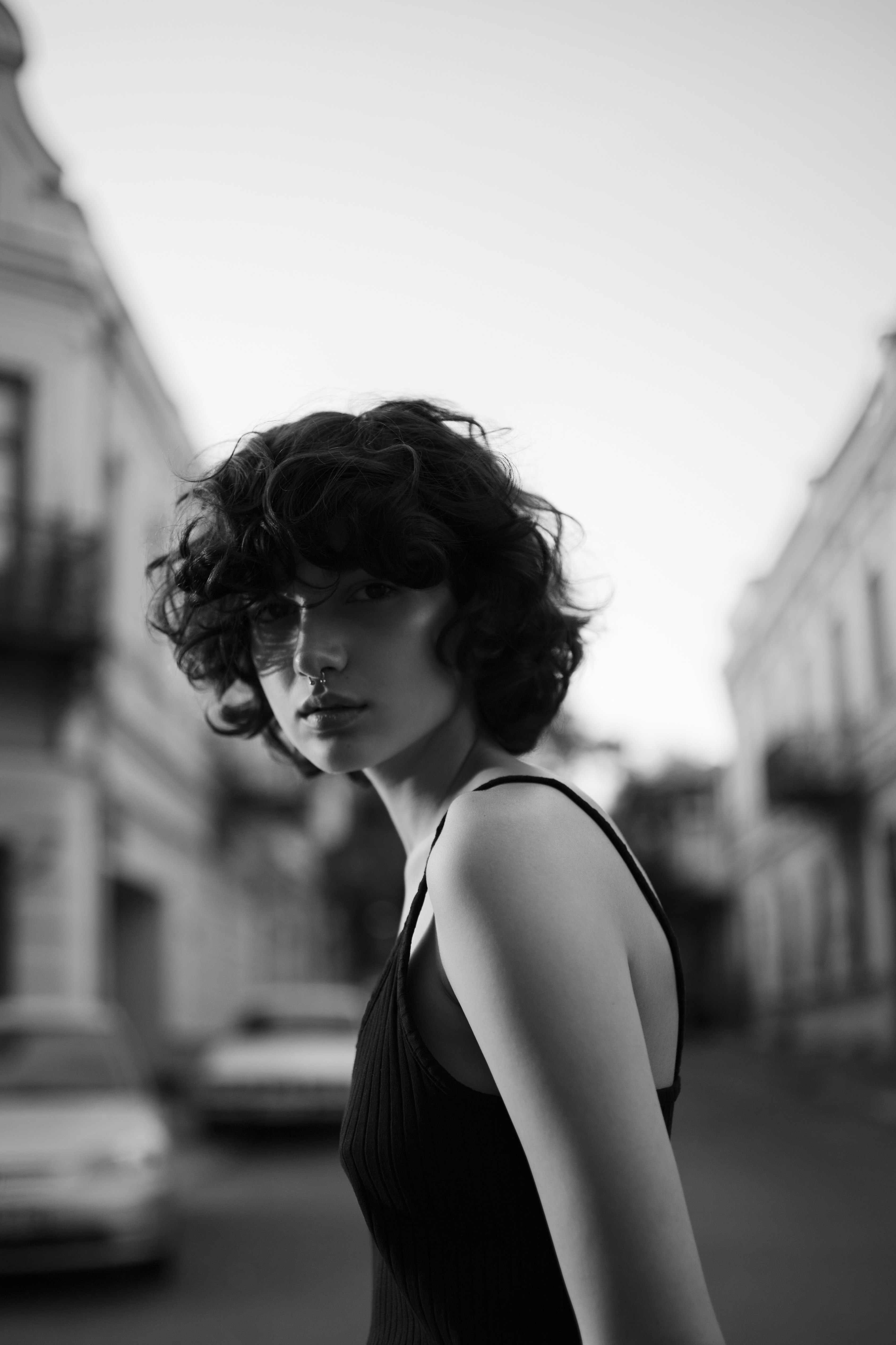 grayscale photography of woman in black spaghetti strap top in middle of road