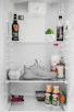 A shiny stainless steel refrigerator stocked with fresh groceries.