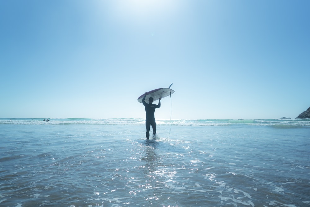 man holds surfboard on water