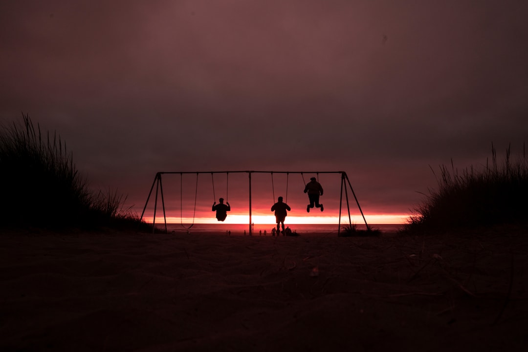 silhouette of three person swinging on outdoor swing
