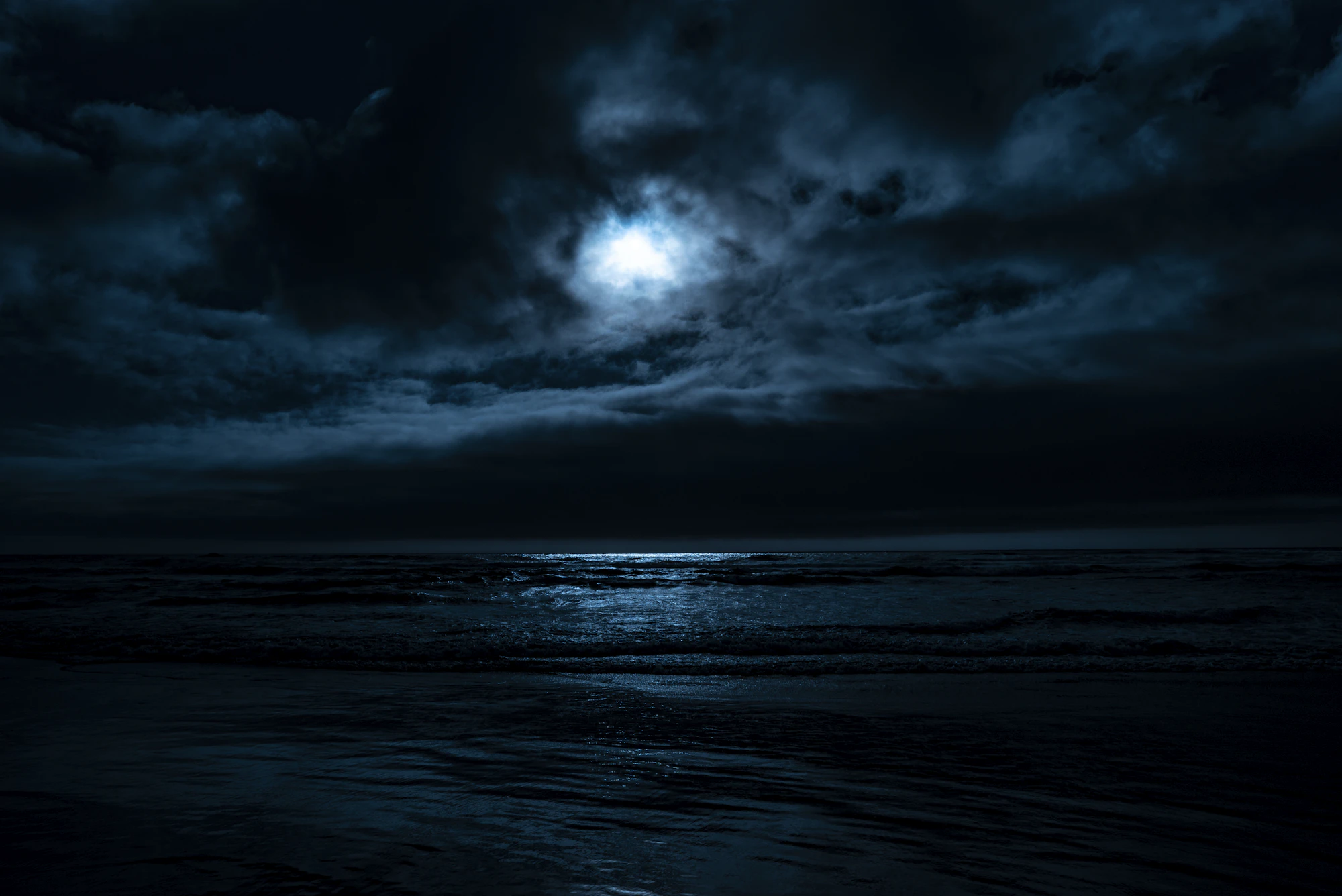 A calm body of water under a full moon at night