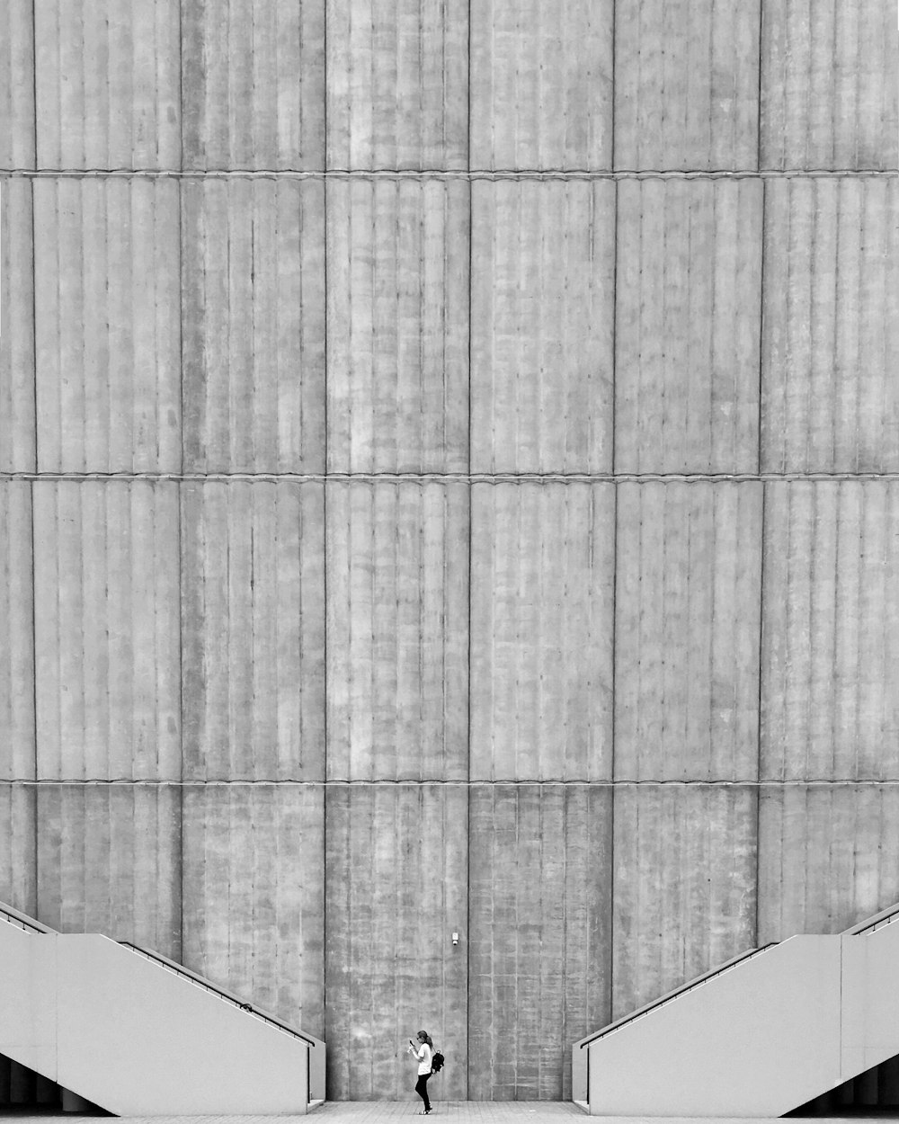 woman standing between two grey concrete stairs beside high-rise building