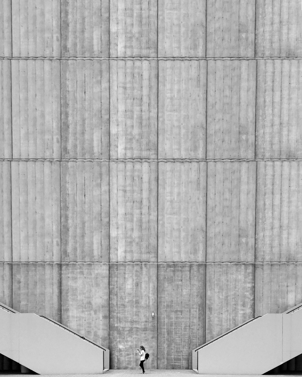 donna in piedi tra due scale di cemento grigio accanto a un grattacielo