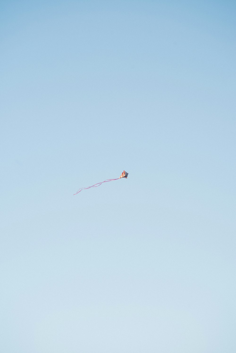 red and white kite flying in the sky