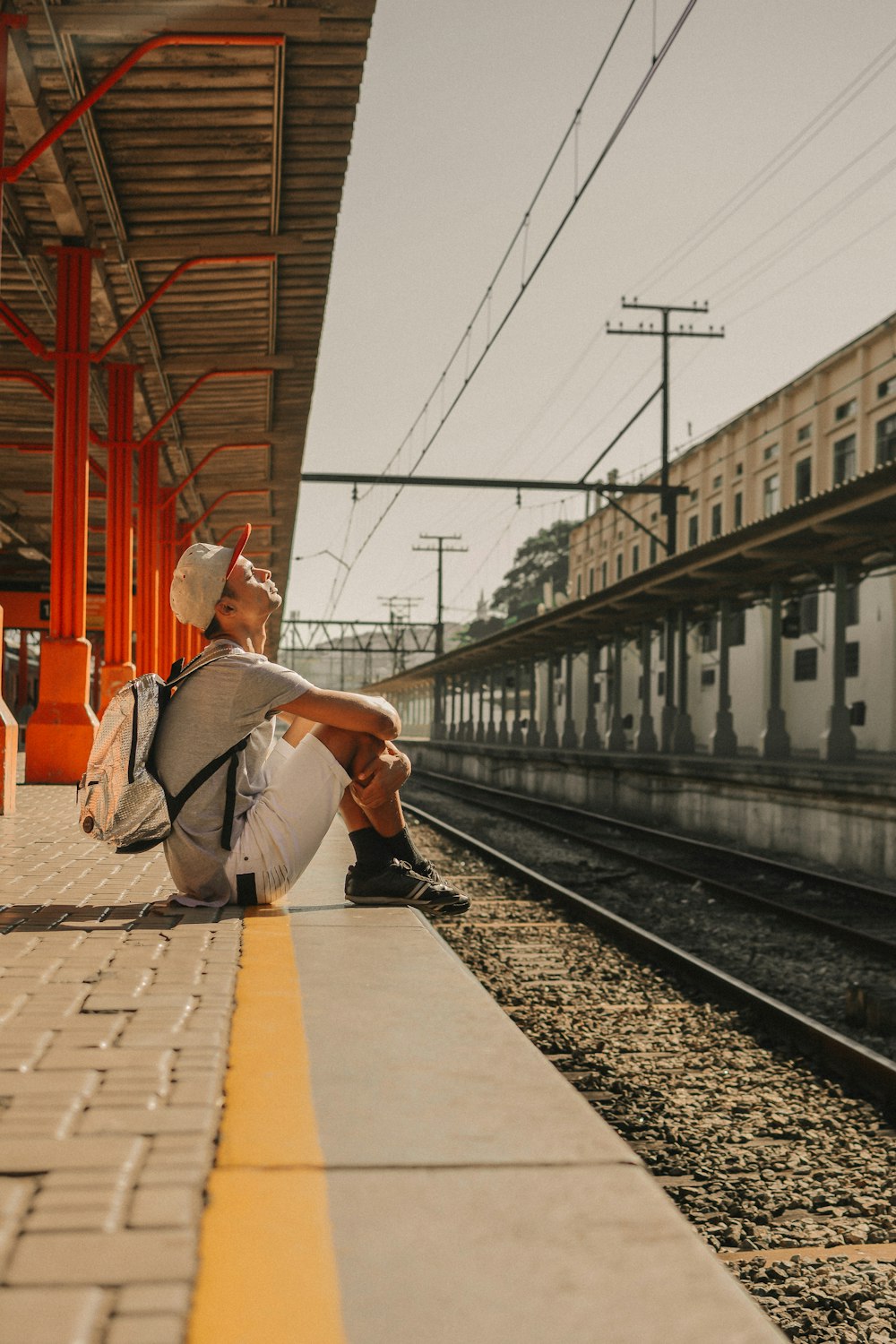 Mann sitzt auf Bürgersteig am Bahnhof