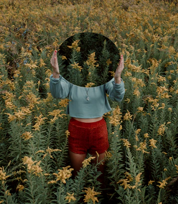 standing woman surrounded by yellow flower field during daytime