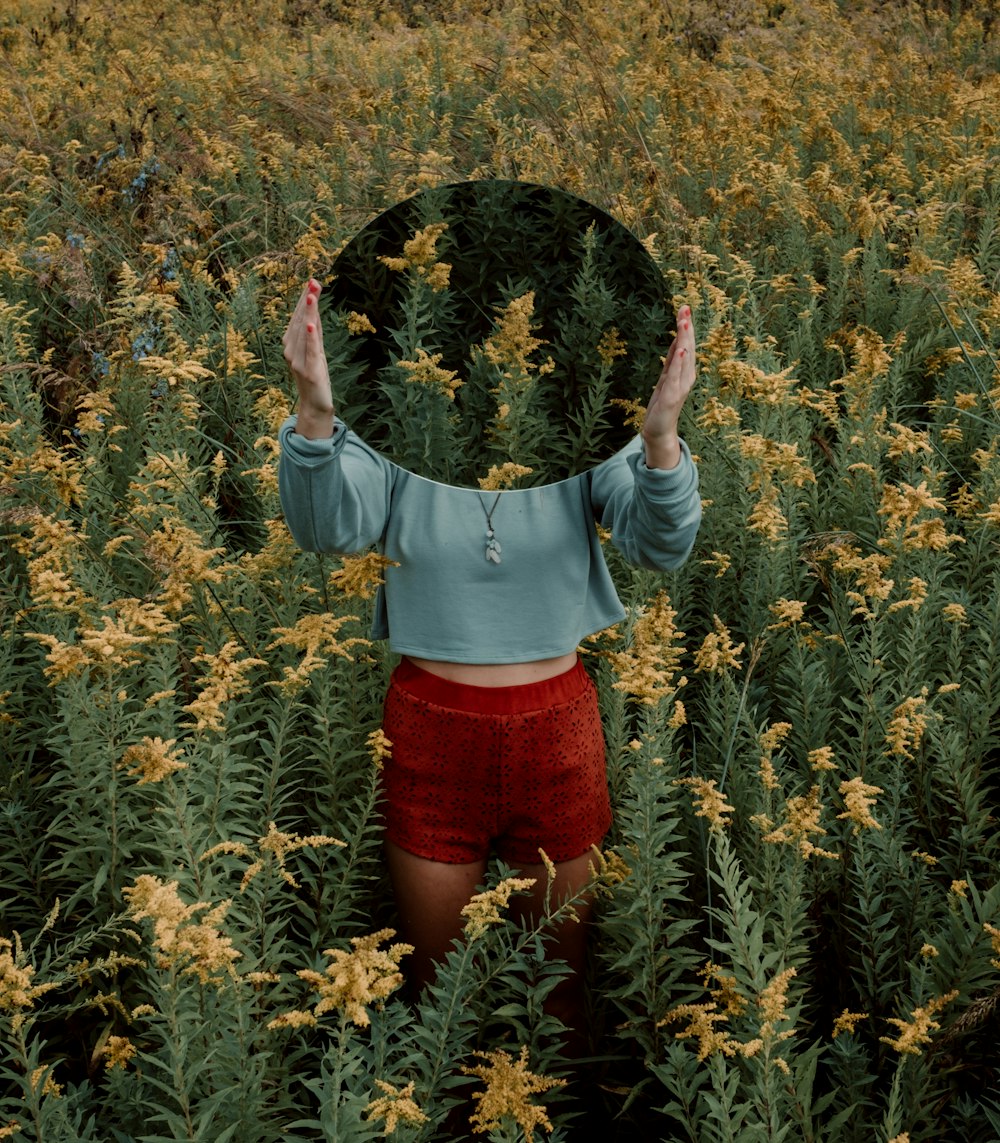femme debout entourée d'un champ de fleurs jaunes pendant la journée