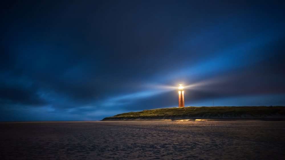 lighthouse under cloudy sky during nighttime