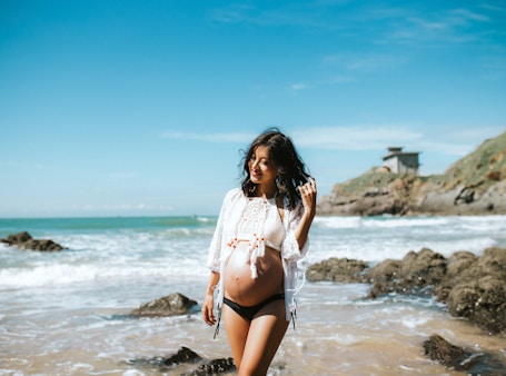 pregnant woman walking on seashore