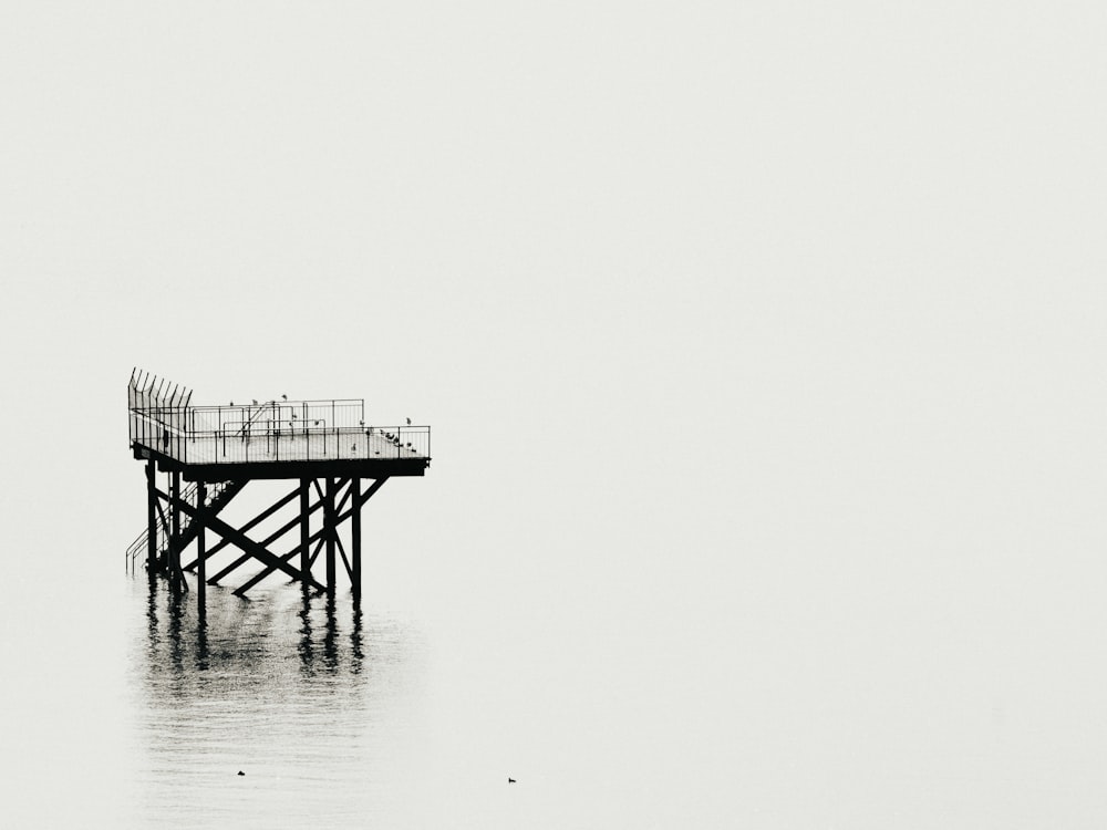 Graustufenfotografie des Turms über einem ruhigen Gewässer