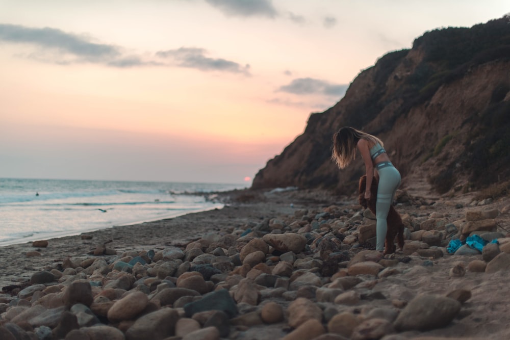 femme avec un chien brun sur une plage