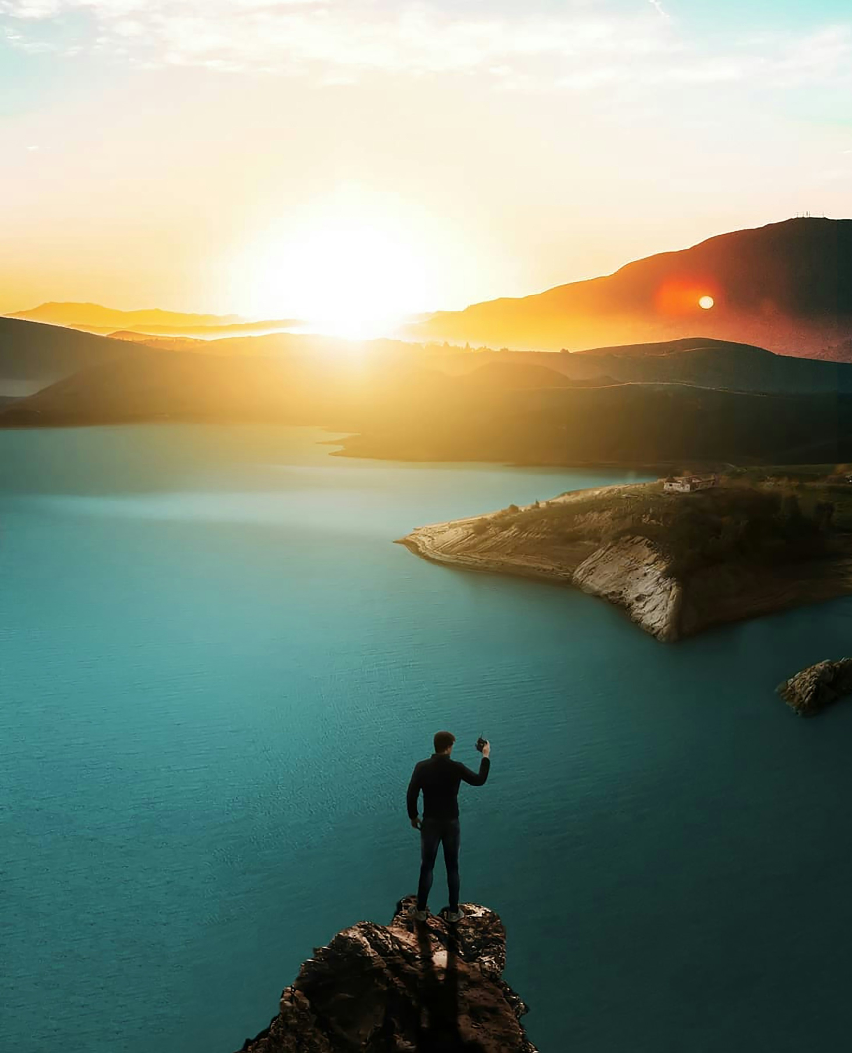 man standing on top of cliff above body of water during golden hour