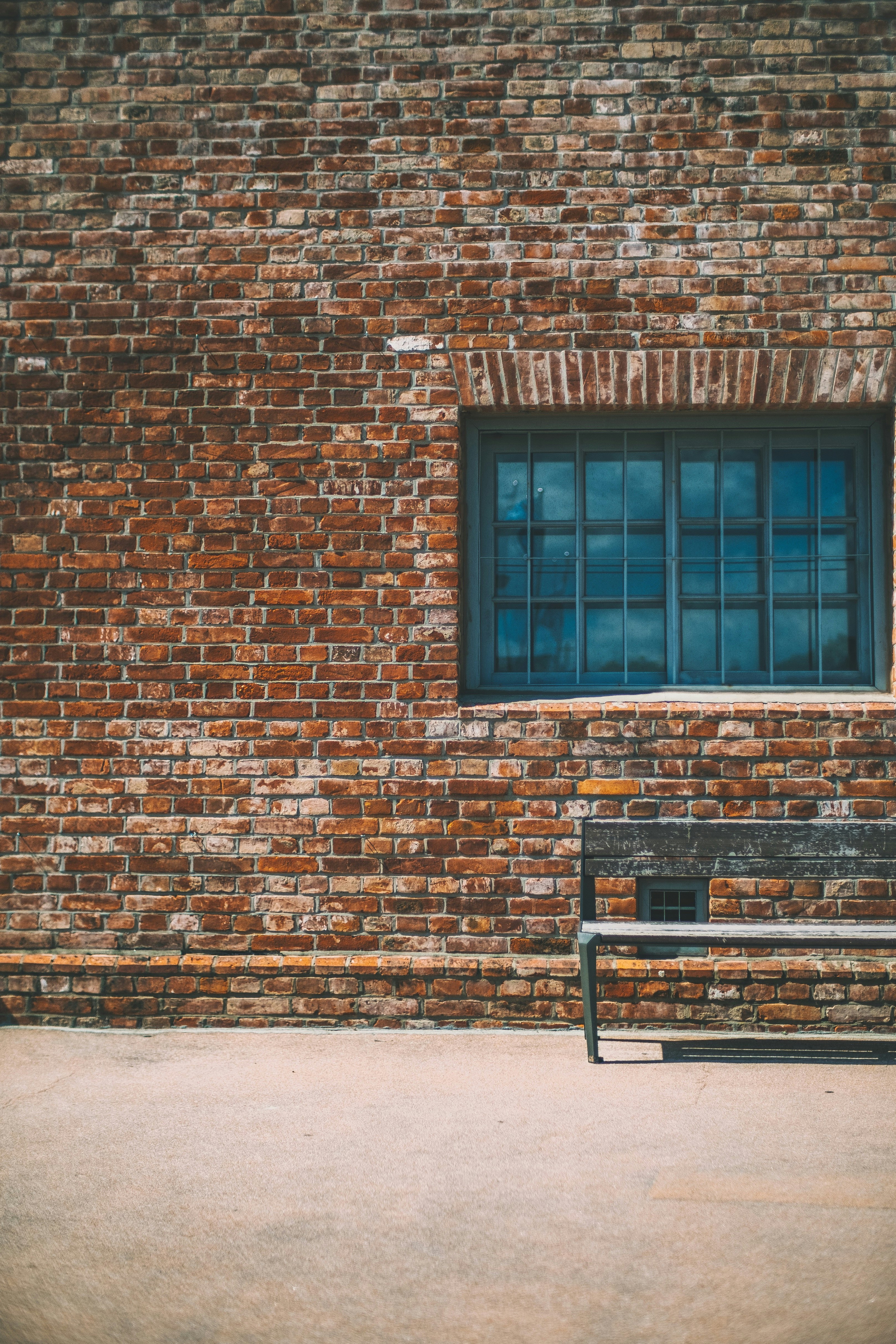 gray bench beside brown brick wall