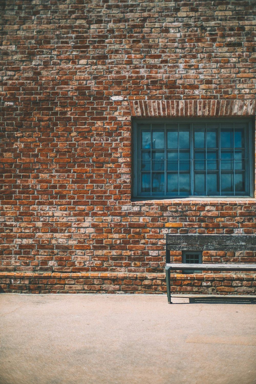 gray bench beside brown brick wall