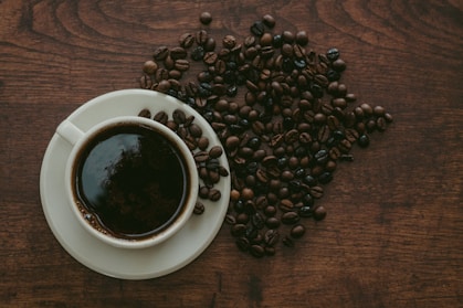 cup of coffee surrounded by beans
