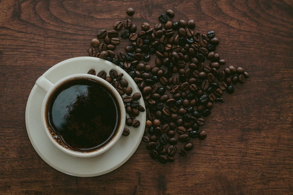 cup of coffee surrounded by beans