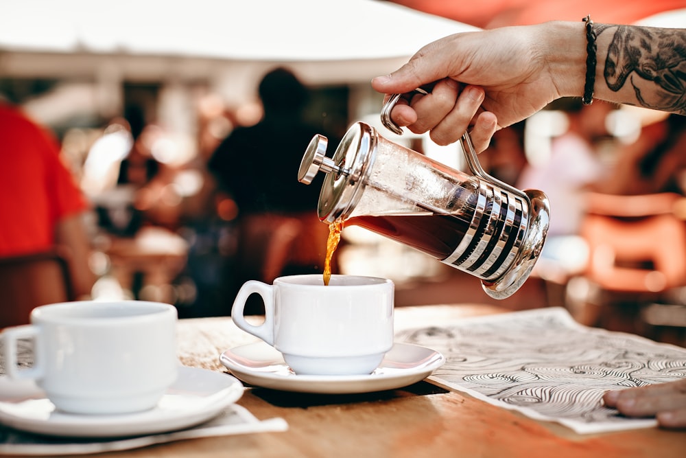 person pouring tea on white teacup